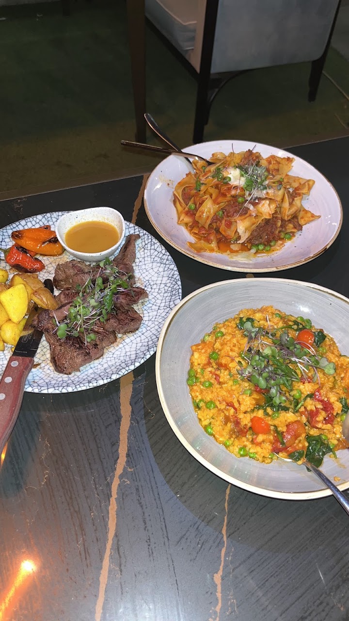 Shared pasta, risotto, and grilled dishes on a table at Planar Restaurant